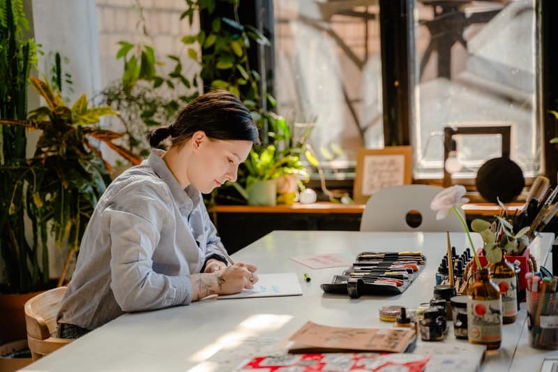 une femme est assise à une table et écrit une lettre