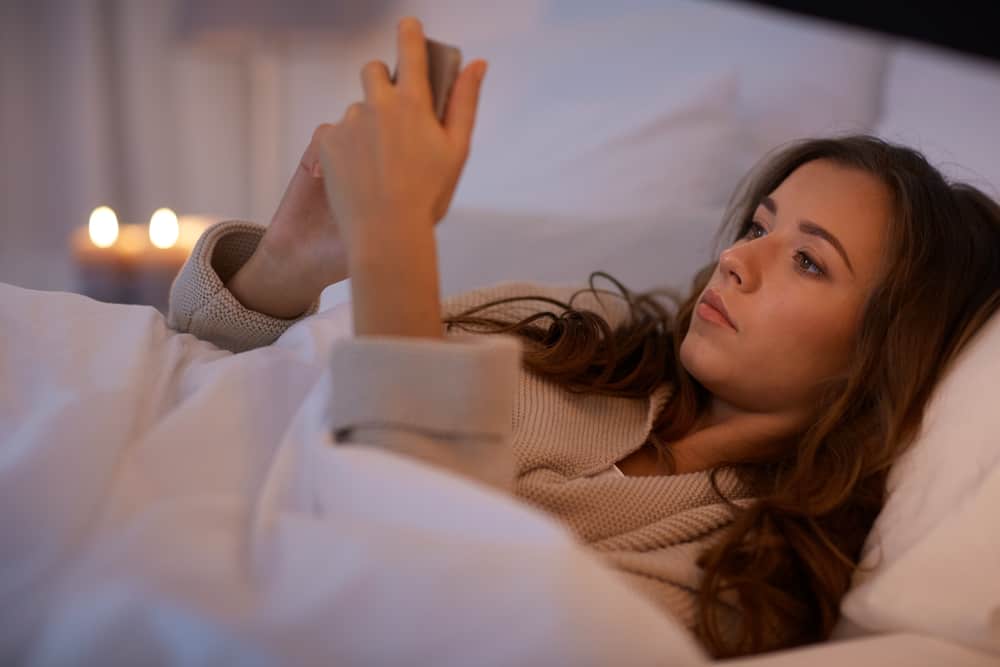 une femme imaginaire au lit lit un sms