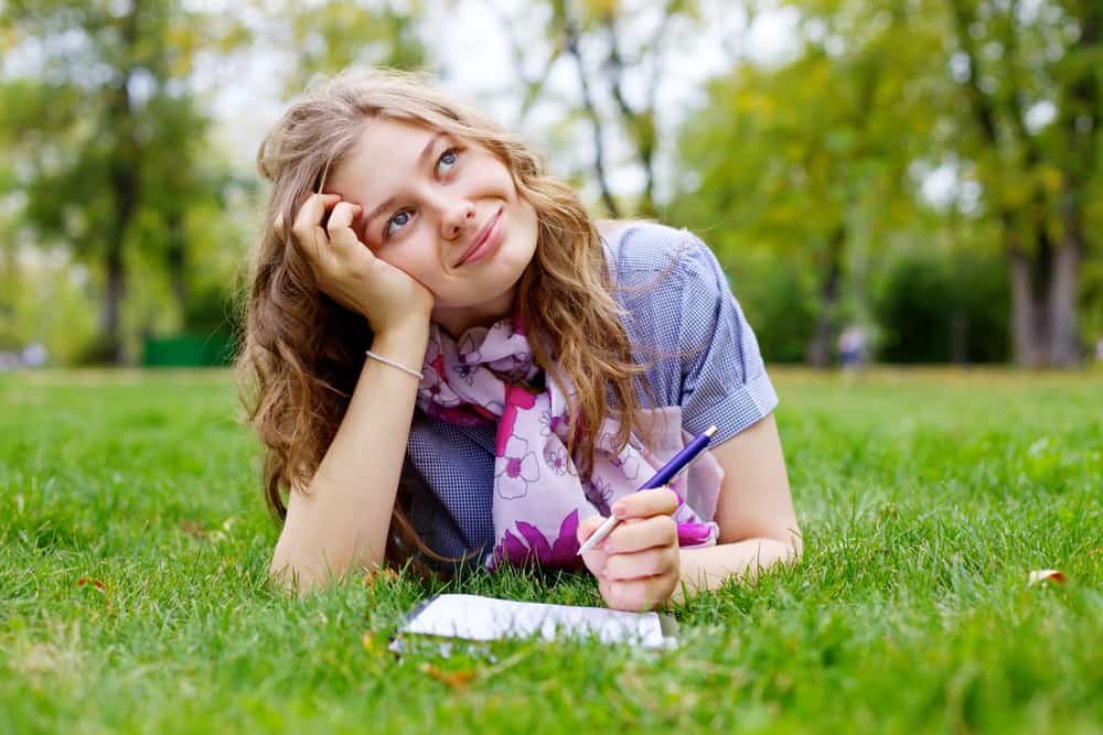 une femme imaginaire se trouve dans l'herbe et écrit