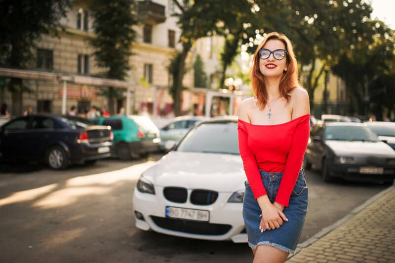 une femme se tient dans la rue avec des lunettes sur la tête