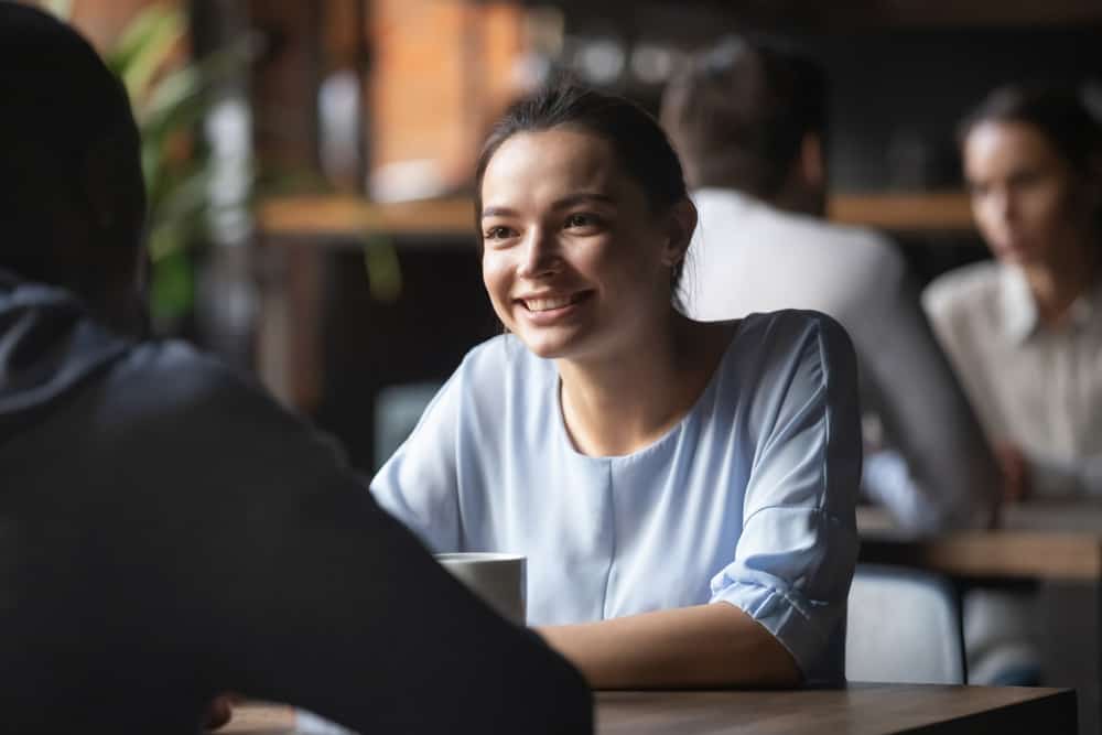 une femme souriante assise avec un homme dans un café et parler