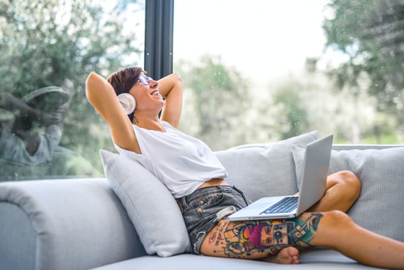 une femme souriante avec un casque sur la tête est allongée sur le lit
