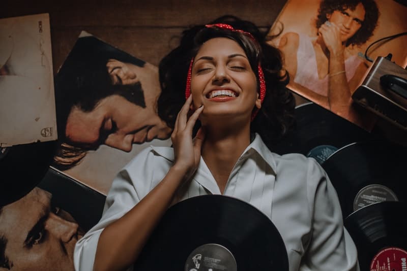 une femme souriante est allongée sur le sol et écoute les disques