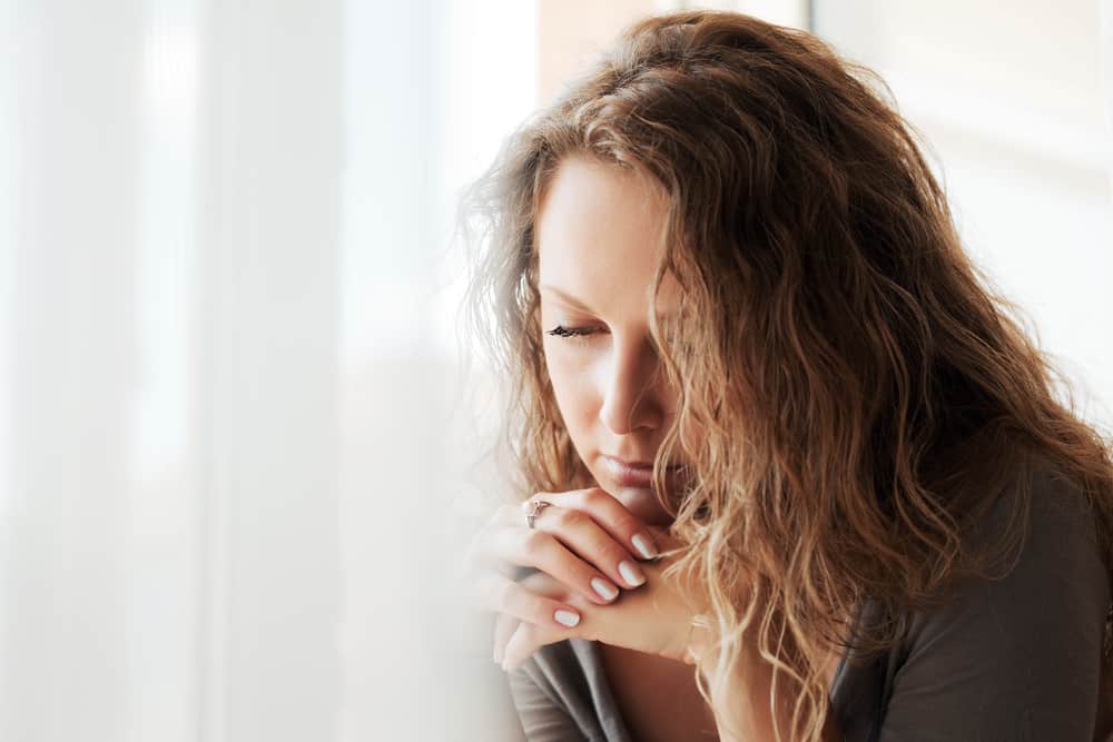une femme triste assise près de la fenêtre
