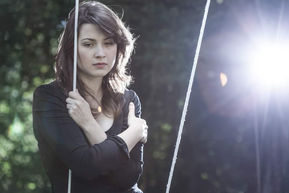 une femme triste dans la soirée est assise sur une balançoire à l'extérieur