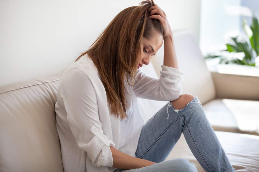 une femme triste est assise sur le canapé