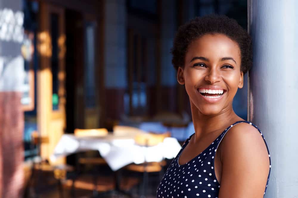 une femme à la peau noire se lève et rit