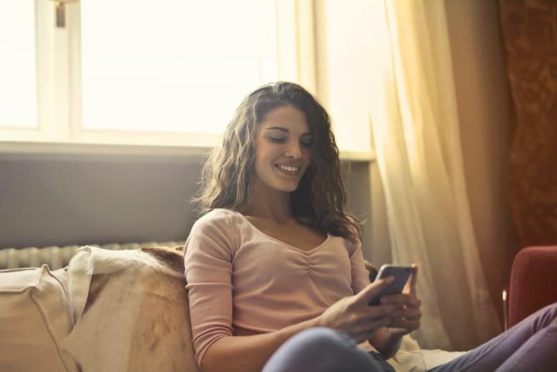 une fille souriante s'assied et écrit un sms