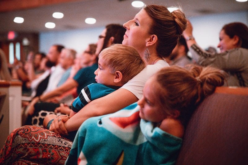 une mère avec deux enfants regarde un film au cinéma