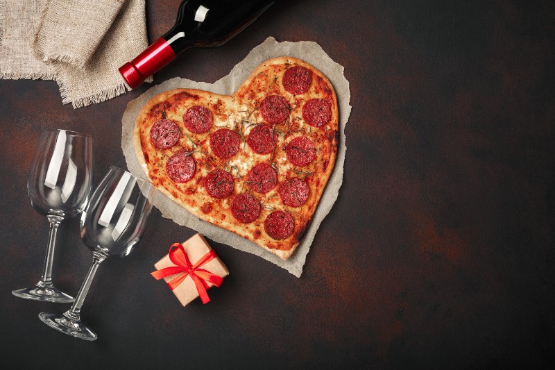 une pizza en forme de cœur et du vin à côté