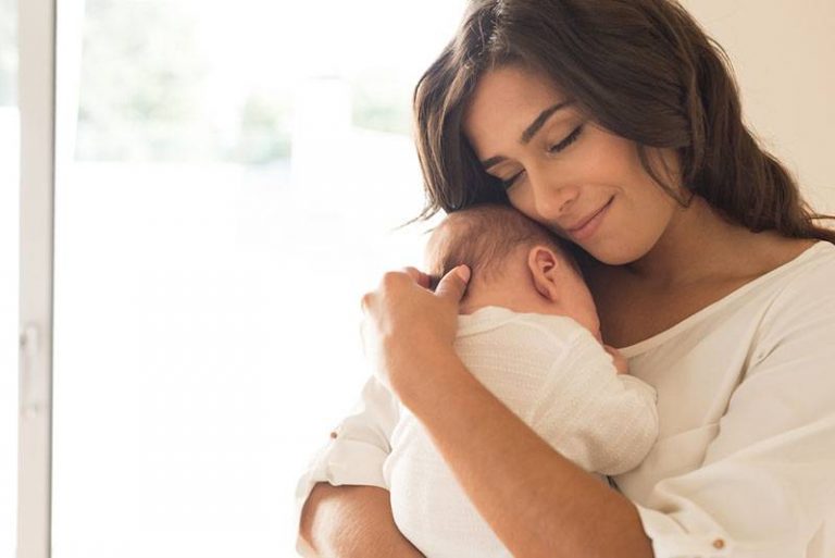 Une mère embrasse son bébé à la maison