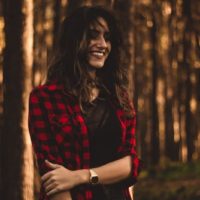 une femme debout dans une chemise à carreaux dans les bois