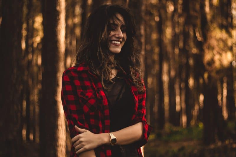 une femme debout dans une chemise à carreaux dans les bois
