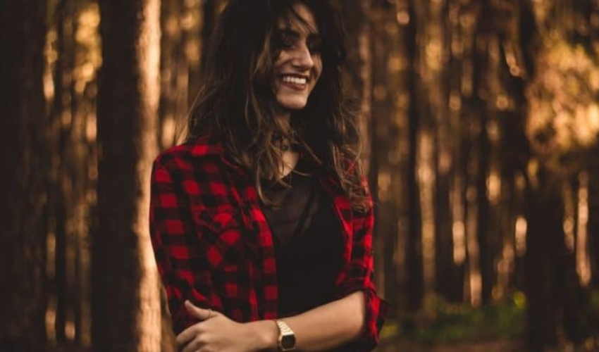 une femme debout dans une chemise a carreaux dans les bois