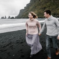 un homme et une femme courent le long de la plage main dans la main