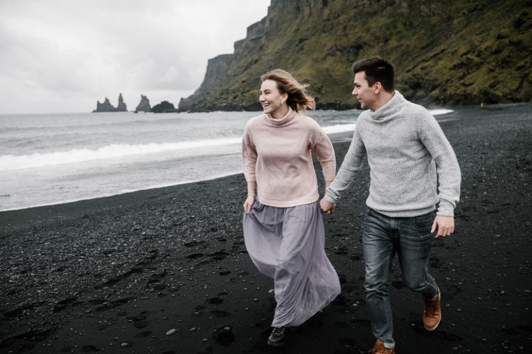 un homme et une femme courent le long de la plage main dans la main
