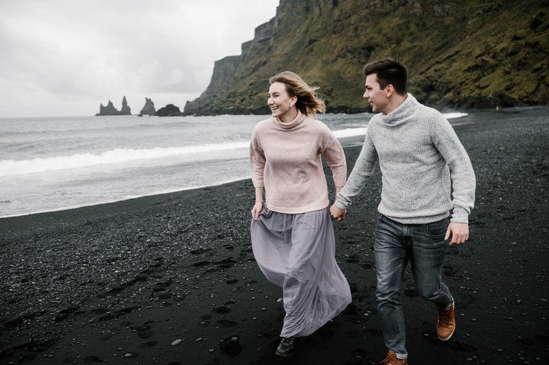 un homme et une femme courent le long de la plage main dans la main