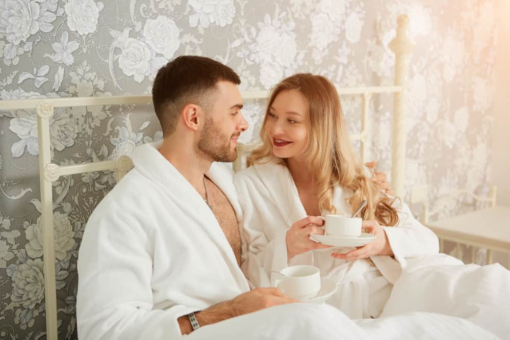 Couple romantique au lit tenant une tasse de café et profitant de la matinée de lune de miel sur le lit