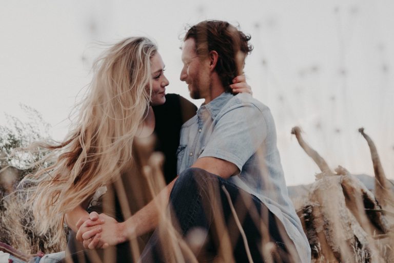 un homme et une femme s'embrassent assis sur l'herbe