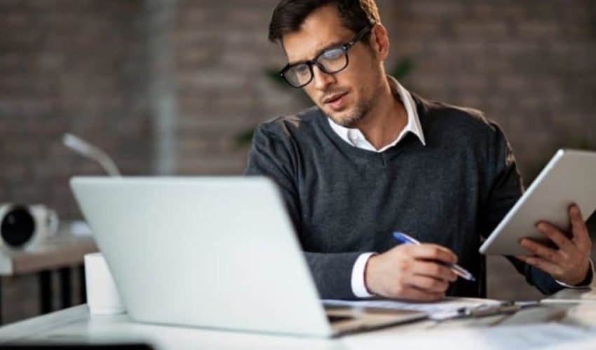 un homme est assis devant un ordinateur portable et travaille