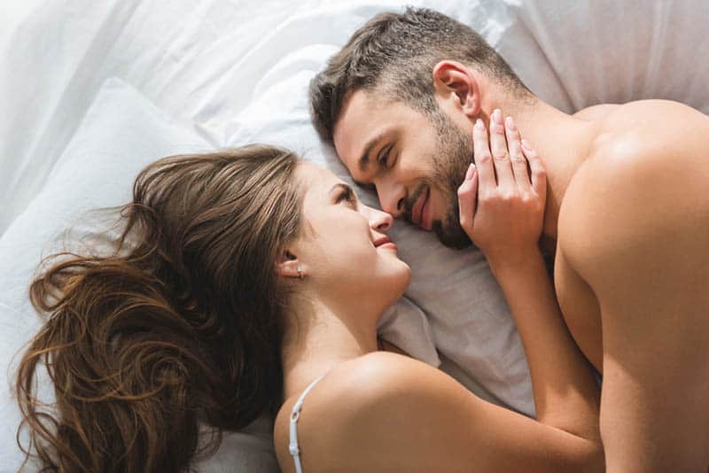 couple romantique se regardant et s'allongeant sur le lit