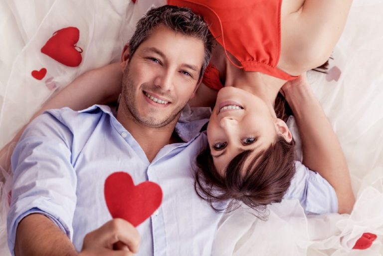 un homme et une femme heureux montrant un coeur rouge