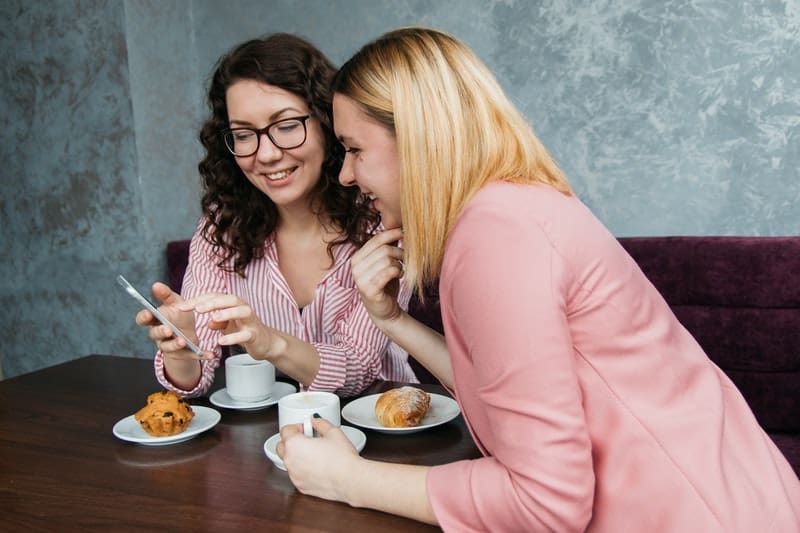 deux amis sont assis à une table en regardant le téléphone