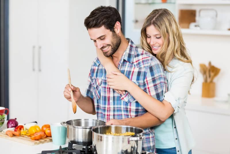 Un jeune couple souriant, cuisiner des aliments dans la cuisine