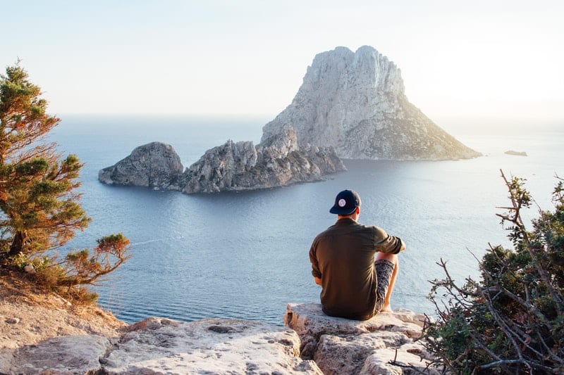 un homme est assis sur un rocher et regarde la mer