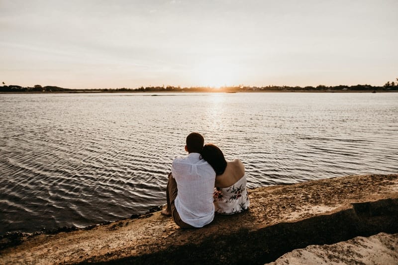 un homme et une femme assis embrassés par la mer