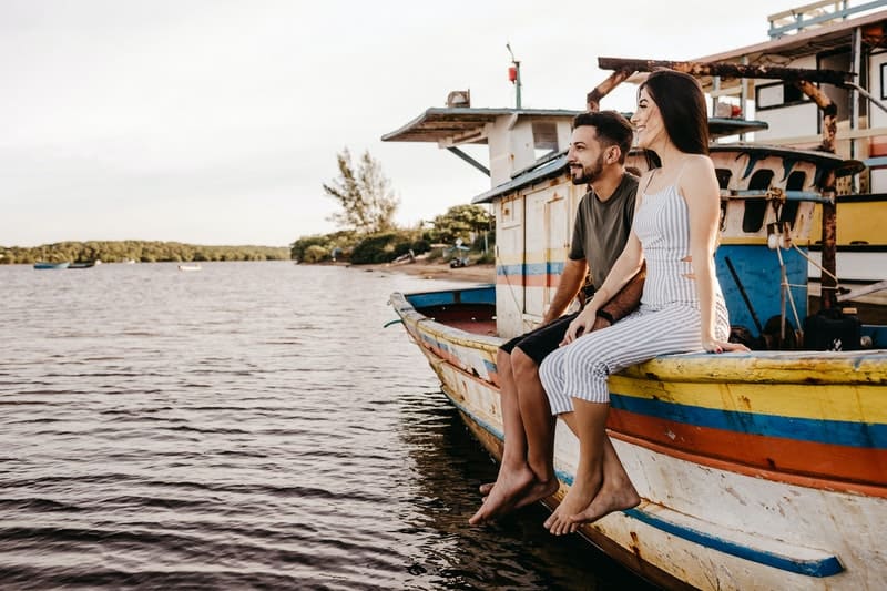 un homme et une femme s'assoient sur un bateau et rient