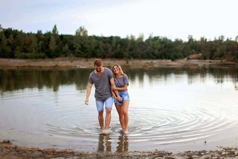 un homme et une femme se tiennent dans la rivière et rient