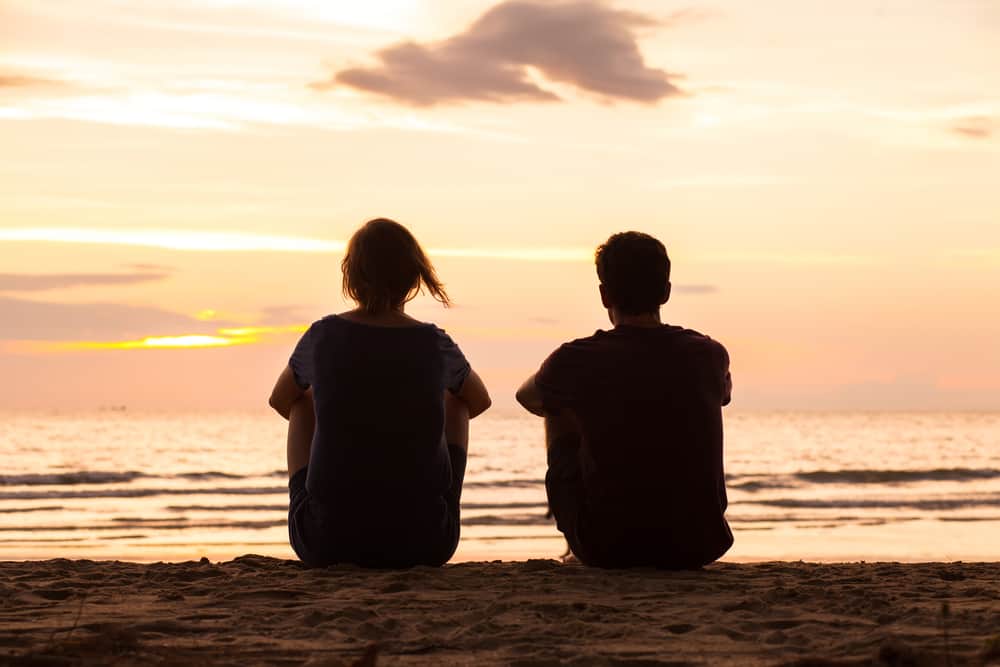 un homme et une femme sont assis au bord de la plage
