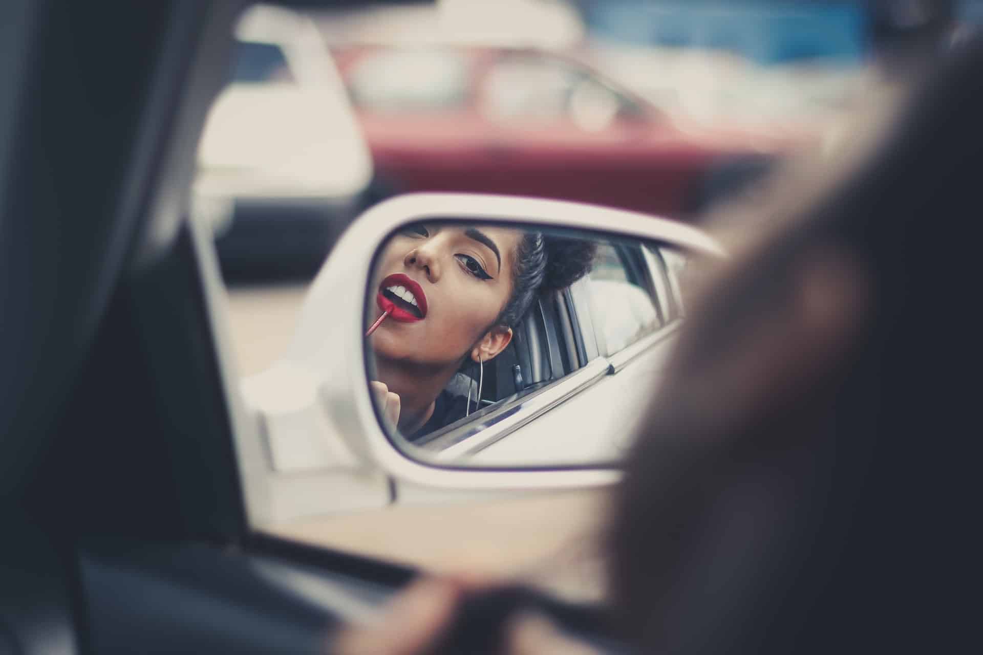 une femme fixe le rouge à lèvres dans une voiture