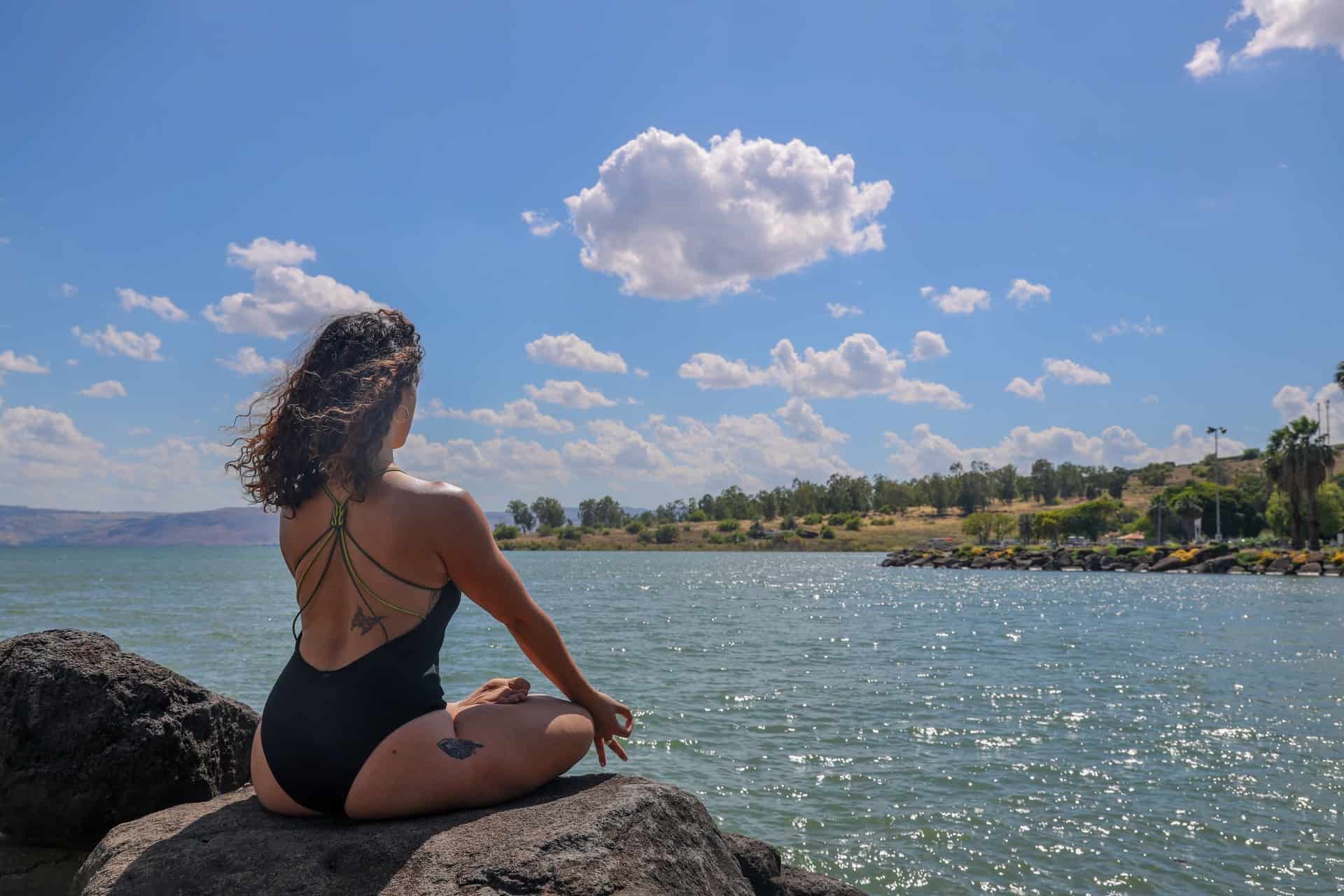 une femme médite sur un rocher au bord de la mer