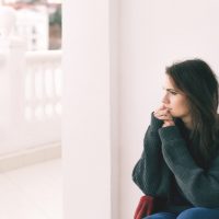 une femme triste regarde par la fenêtre