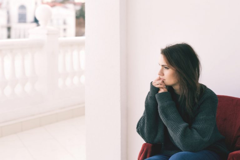 une femme triste regarde par la fenêtre