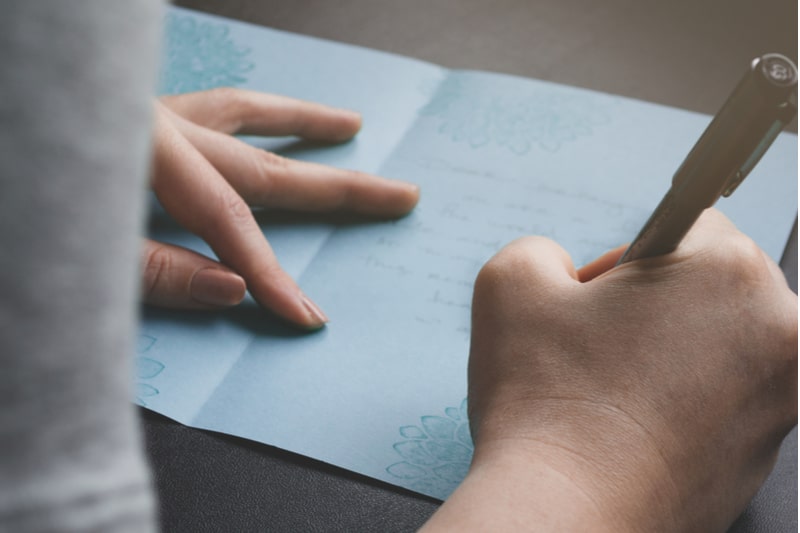 Dame écrivant une carte fabriquée à la main à la famille ou à un ami