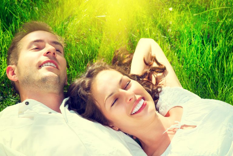 un homme et une femme s'allongent sur l'herbe et rient
