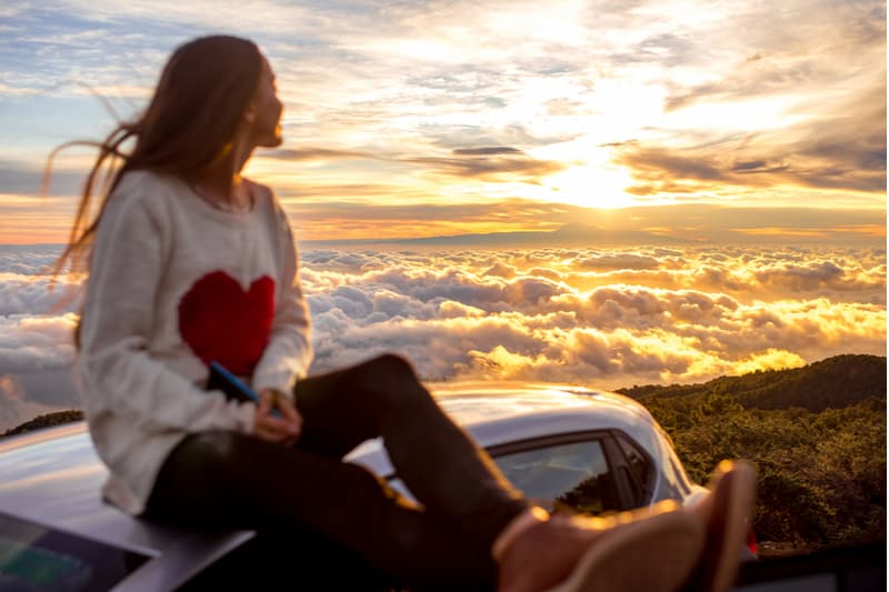 Jeune femme en pull avec forme de coeur bénéficiant de beaux cloudscape