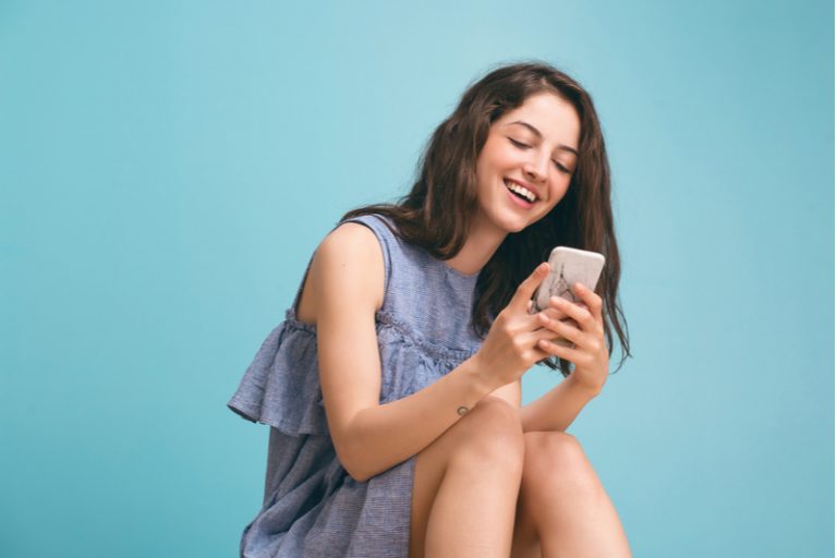 une femme avec un téléphone à la main rit
