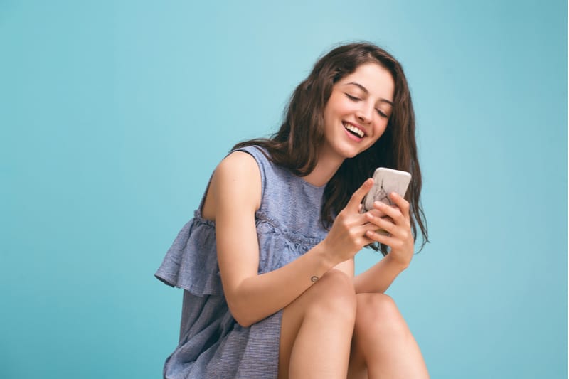 une femme avec un téléphone à la main rit