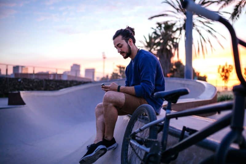 un homme assis sur un banc avec un téléphone à la main