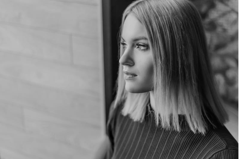 jeune femme séduisante regarde par la fenêtre avec un regard triste
