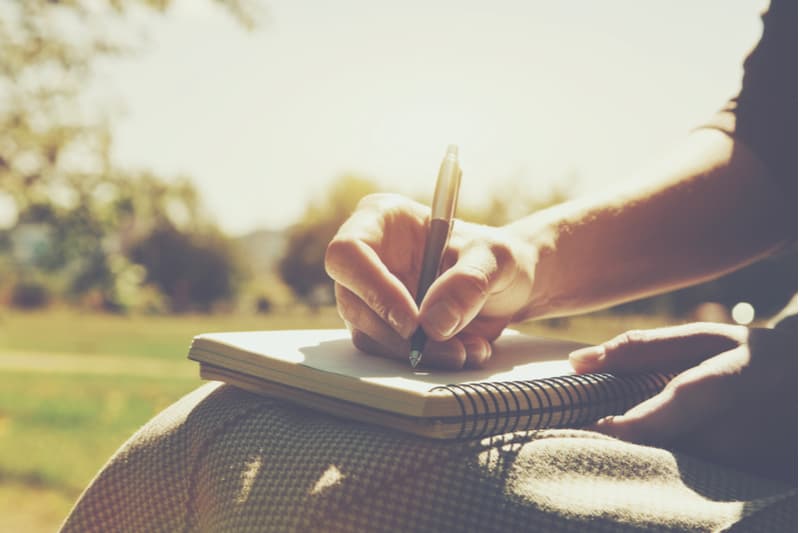 mains de filles avec stylo écrit sur ordinateur portable dans le parc