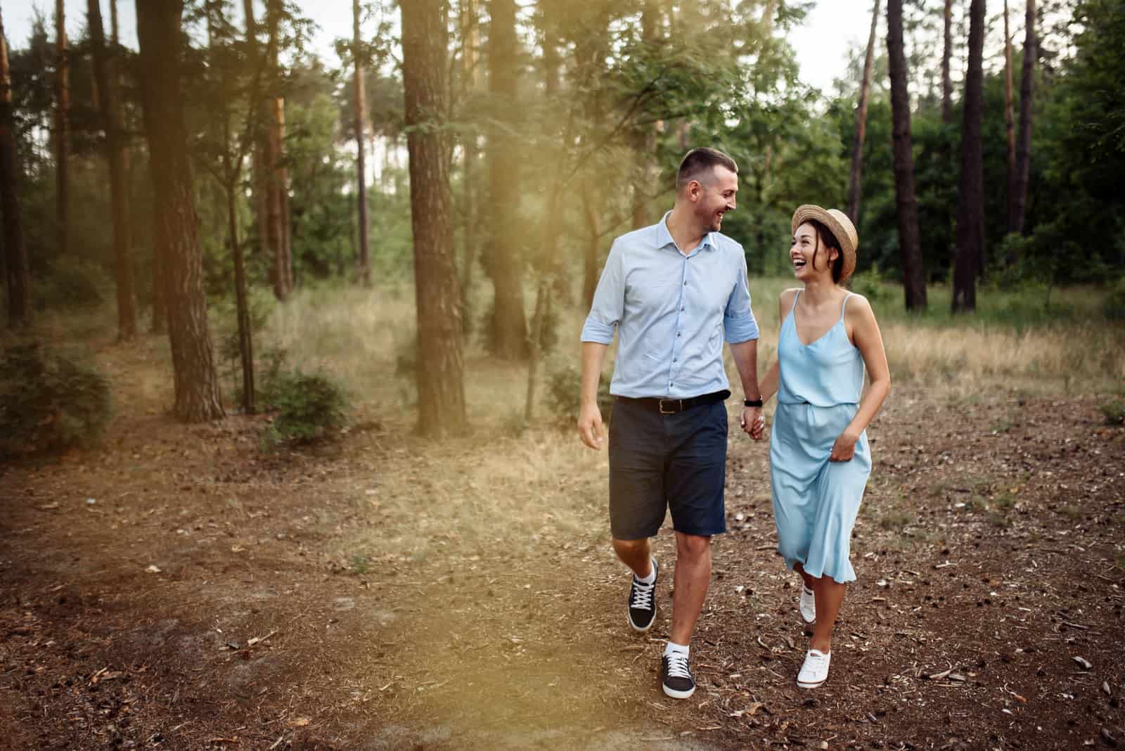 un homme et une femme marchent dans les bois et rient