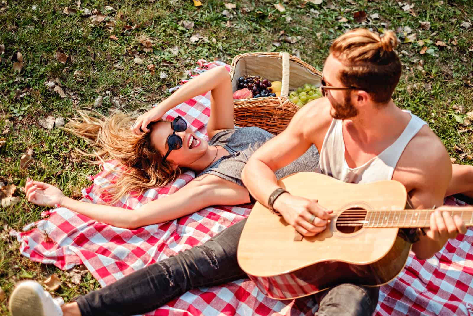 un homme jouant de la guitare une femme allongée sur l'herbe