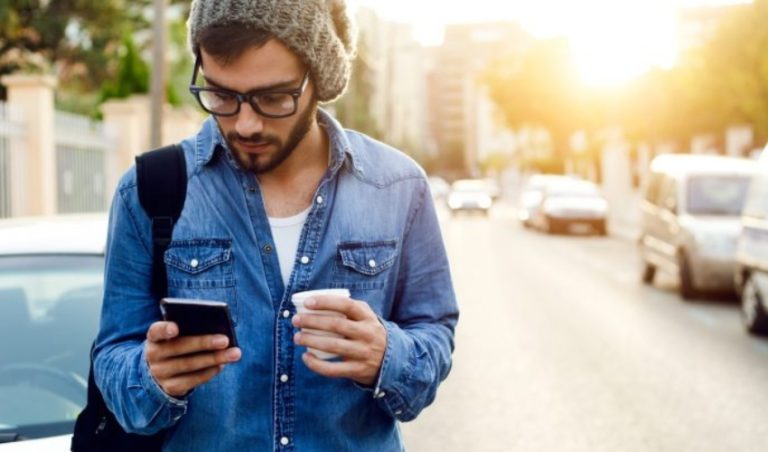 un homme debout avec un telephone a la main