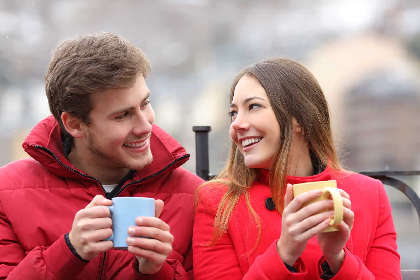 Couple parlant détendu assis sur un banc avec des tasses à café en hiver