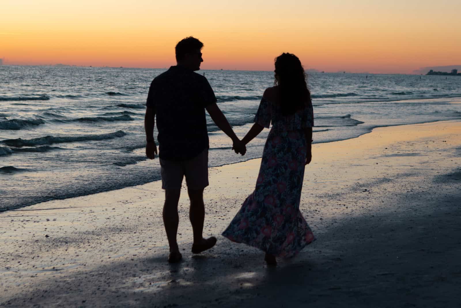 couple main dans la main et marchant le long de la plage